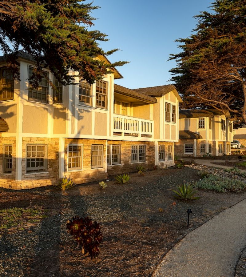 A two-story hotel building with a stone and stucco exterior, featuring balconies and multiple windows.
