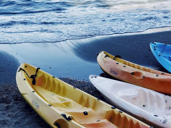 Colorful kayaks on a shoreline with calm water and gentle waves, ready for a paddle adventure.